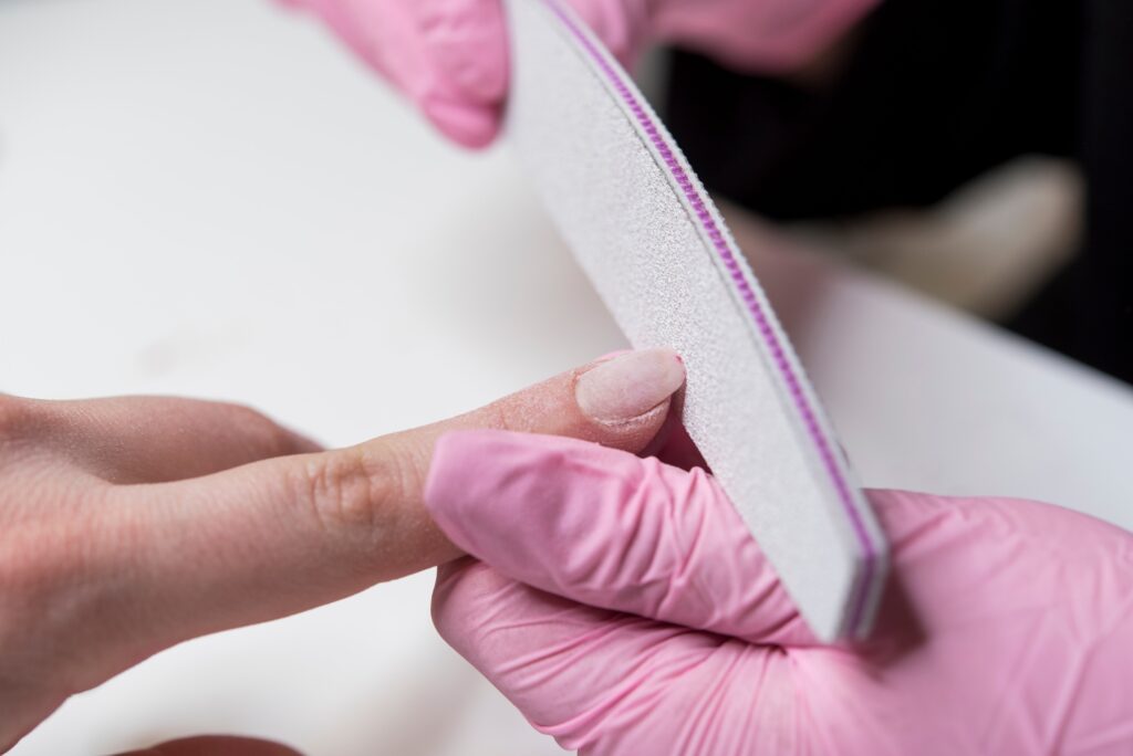 Nail Growth Secrets: Natural Ways to Strengthen and Lengthen Your Nails 8 stock photo closeup shot of a woman in a nail salon receiving a manicure by a beautician with nail file woman shutterstock 1327835345